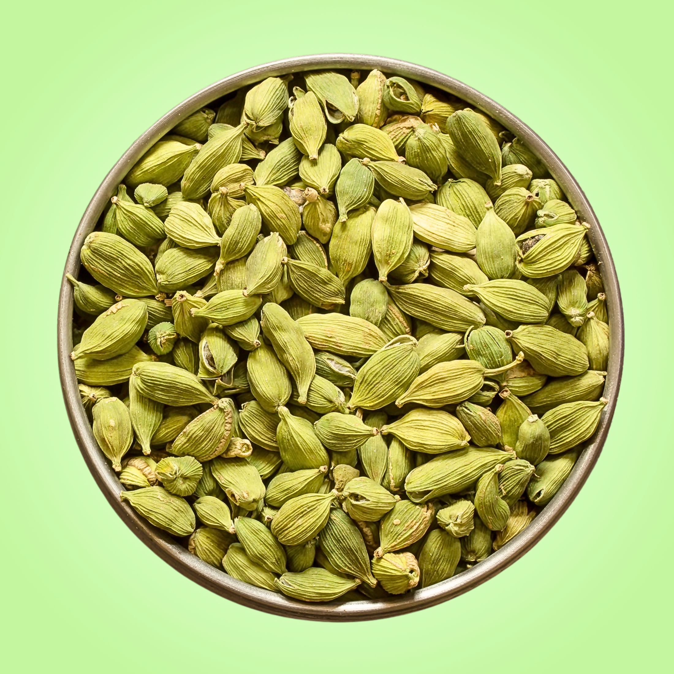 Bowl of green cardamom pods on a green background