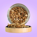 Load image into Gallery viewer, Glass jar with wooden lid containing dried herbs on a purple background
